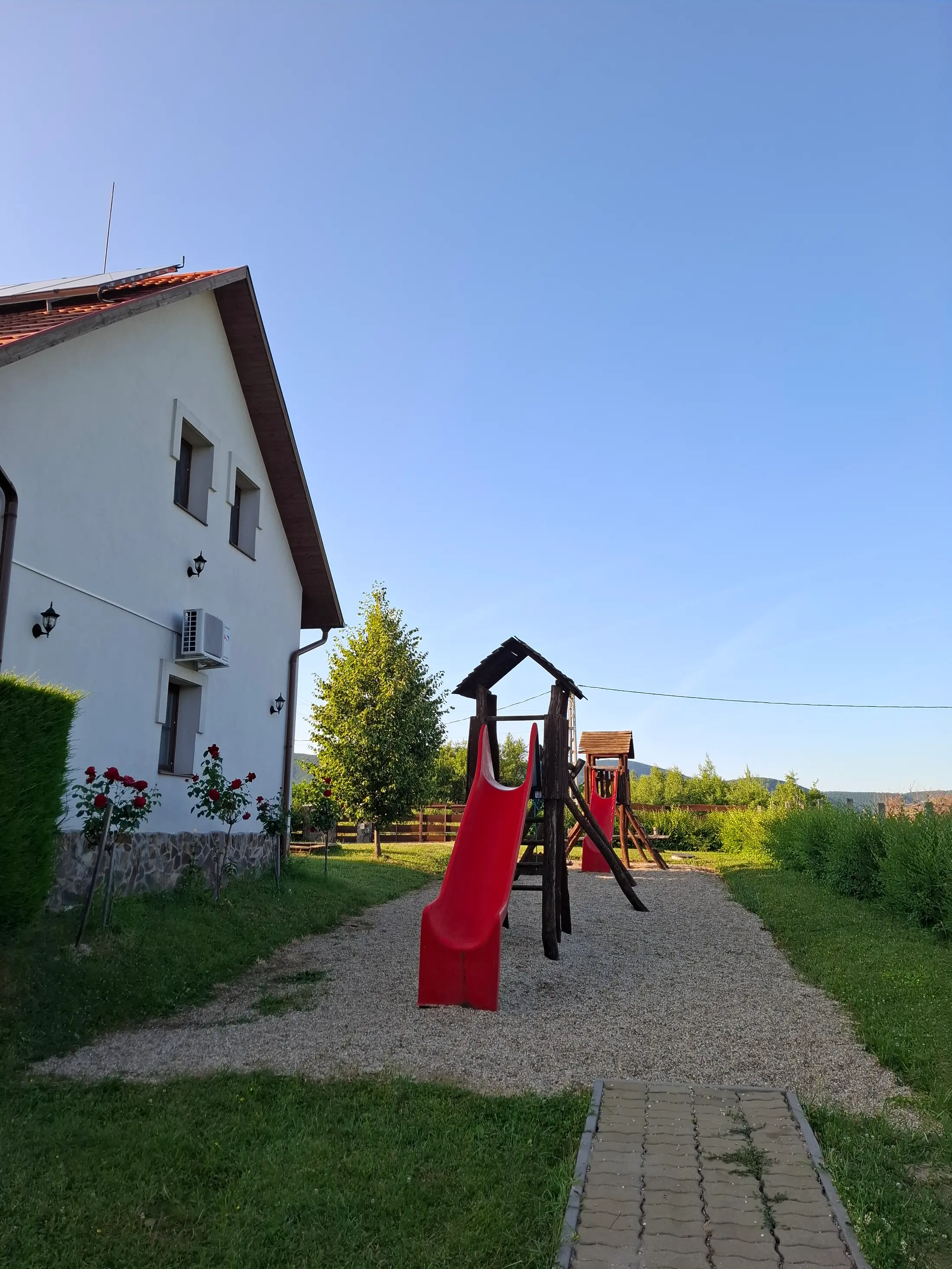 A ház melletti játszótér két csúszdával, hintákkal és mászókával